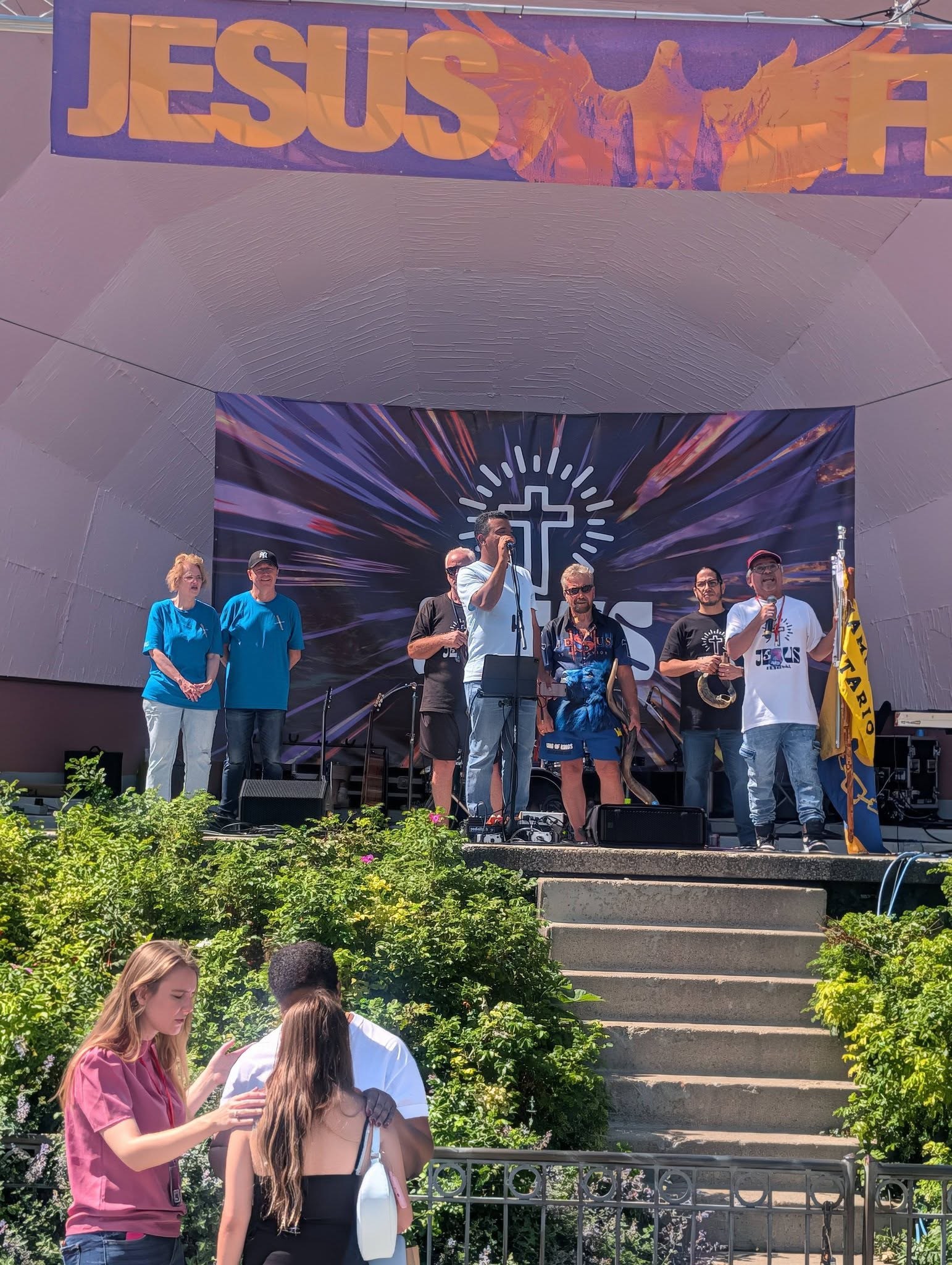 Pastors and leaders on the bandshell stage as prayer happens below